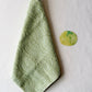 Light green towel with a cabbage illustration next to it on a white background