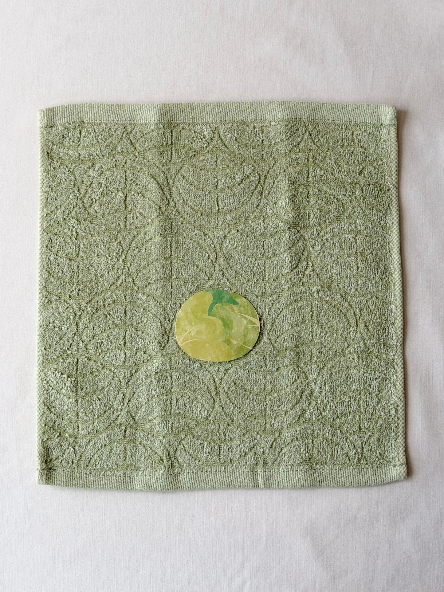 Light green towel with a cabbage illustration in the center on a white background