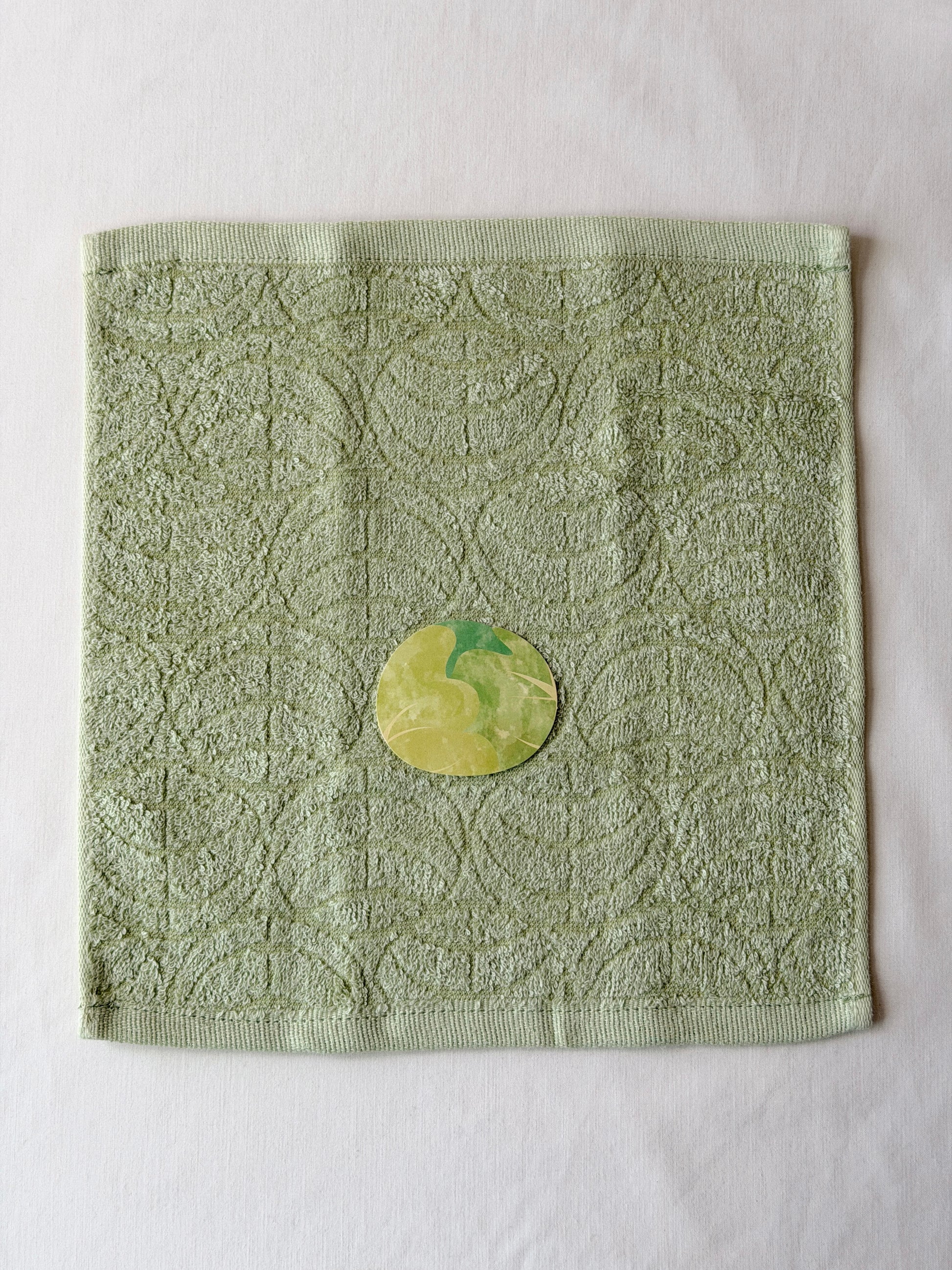 Light green towel with a cabbage illustration in the center on a white background