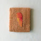 Folded orange towel with a carrot illustration in the center on a white background