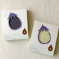 Two packaged towels with a cut-out of an eggplant on each