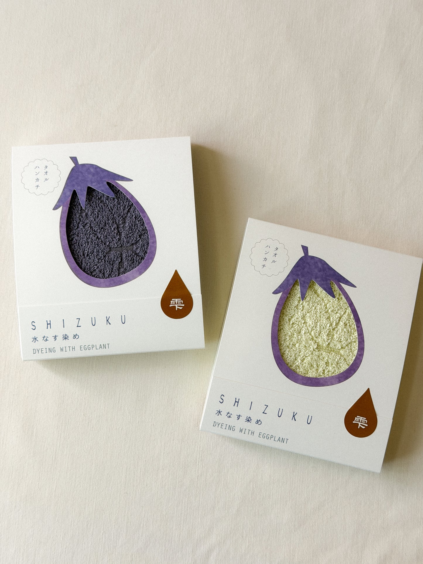 Two packaged towels with a cut-out of an eggplant on each