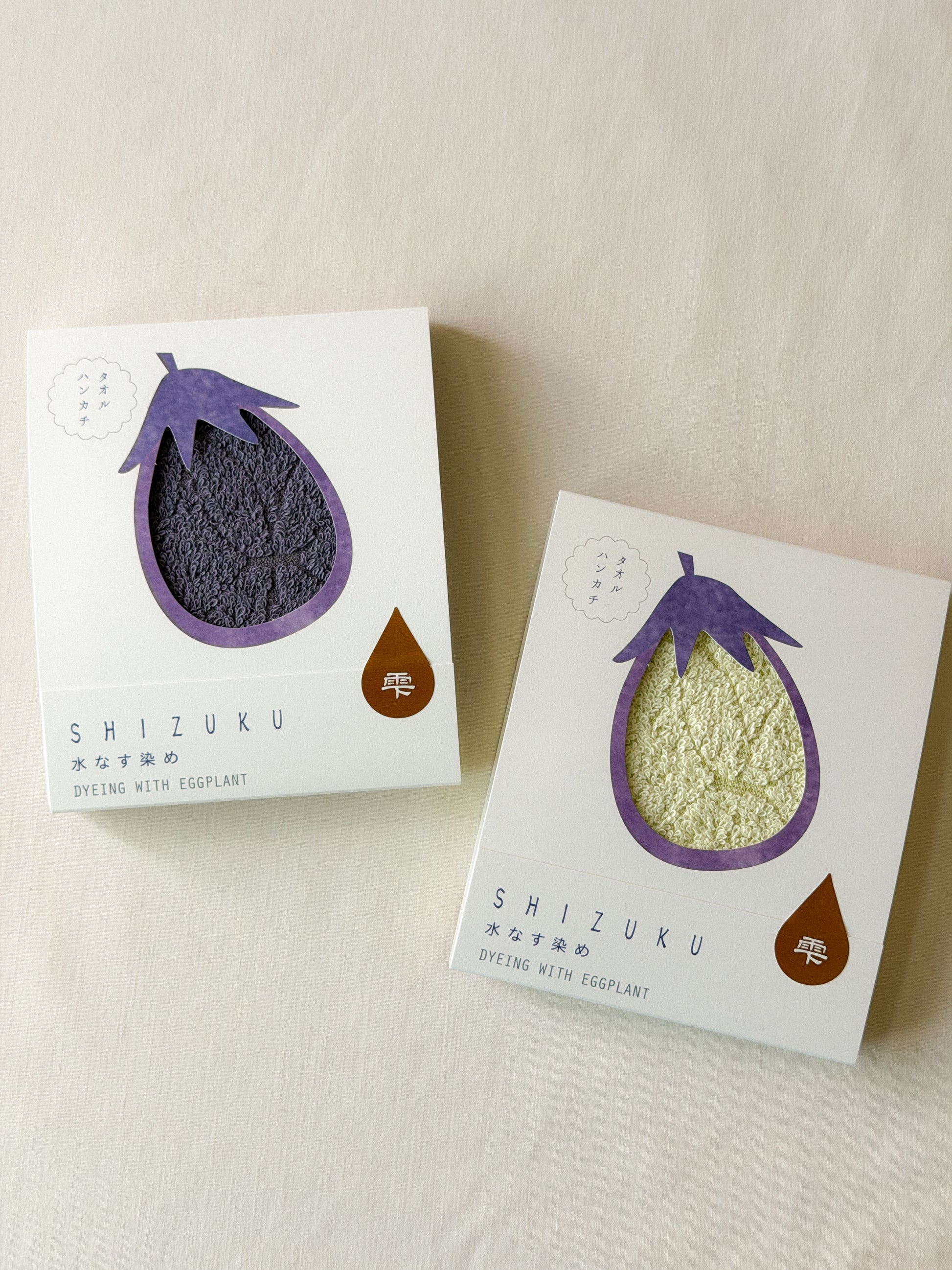 Two packaged towels with a cut-out of an eggplant on each