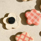 Flower-shaped ceramic magnets with four different checkered design in ivory and pink, some show the back with the magnet