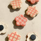 Flower-shaped ceramic magnets with four different checkered design in ivory and pink, some show the back with the magnet