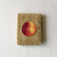 Folded brown towel with an onion illustration in the center on a white background
