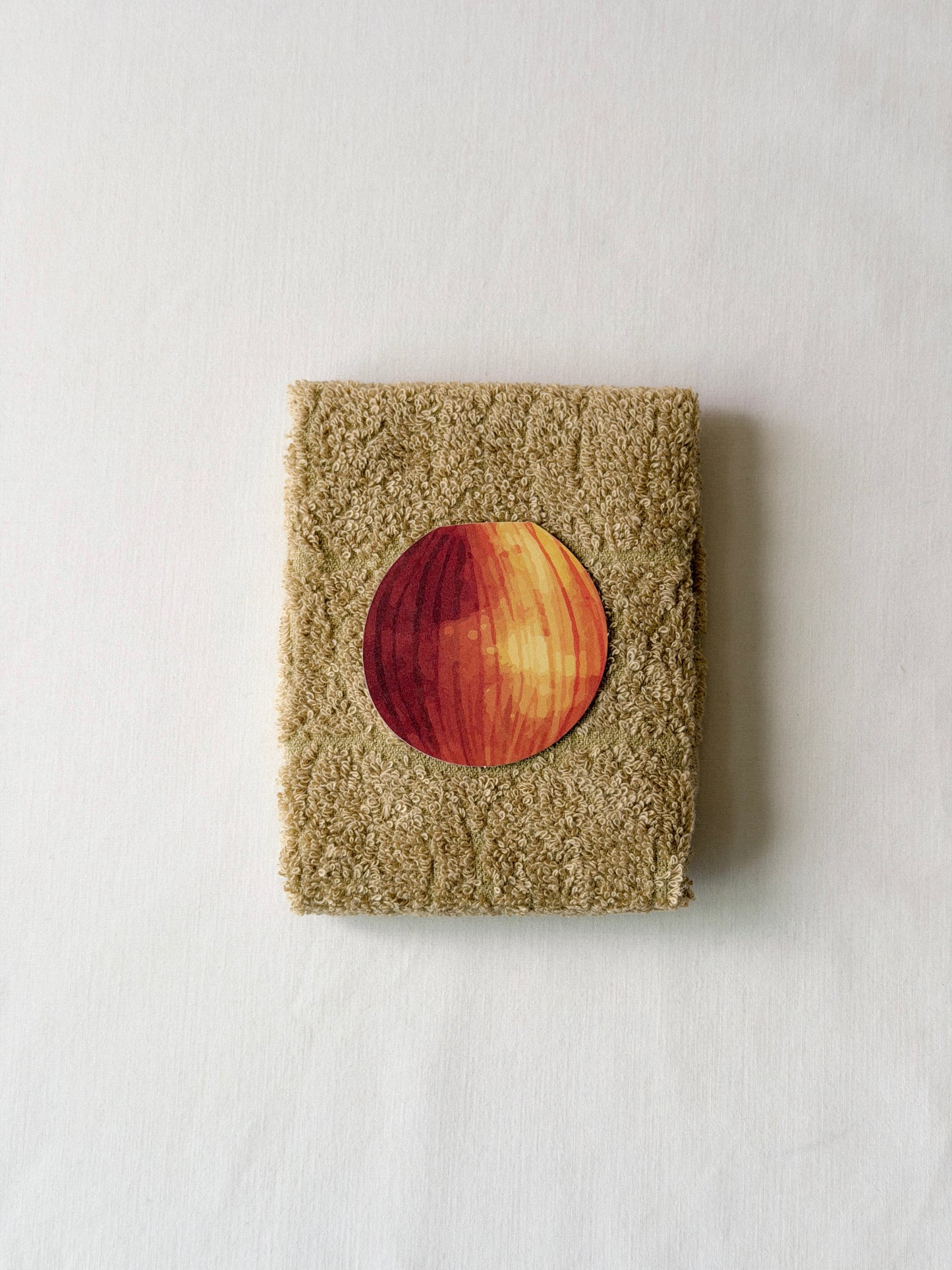 Folded brown towel with an onion illustration in the center on a white background