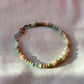 A bracelet made of Czech glass beads, white freshwater pearls, and stainless steel lay flat on a white piece of cloth.