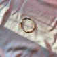 A bracelet made of Czech glass beads, white freshwater pearls, and stainless steel lay flat on a white piece of cloth.