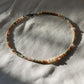 A necklace made of Czech glass beads, white freshwater pearls, and stainless steel lay flat on a white piece of cloth.