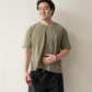 A Chinese man with short hair wearing a yellow brownish green t-shirt and black shorts with his face turned slightly to the side smiling and looking into the distance.