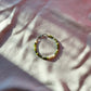 A bracelet made of jade, Japanese glass beads, white freshwater pearls, and stainless steel lay flat on a white piece of cloth.