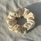 Off white scrunchie lay flat on a white cloth.