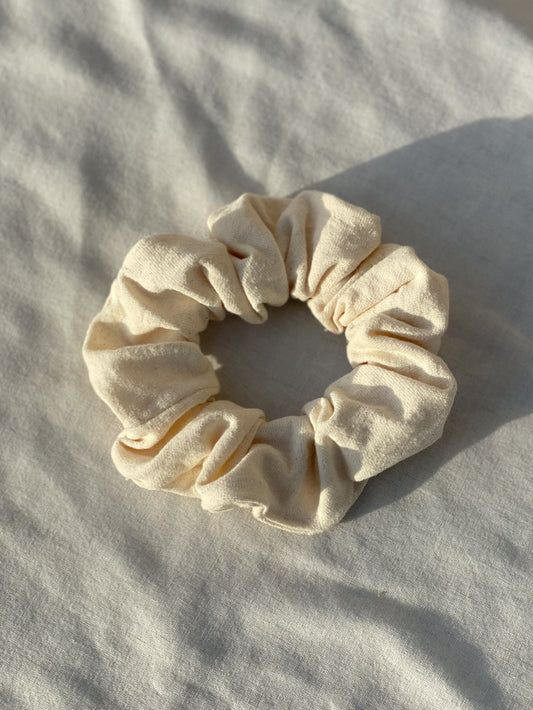 Off white scrunchie lay flat on a white cloth.