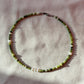 A necklace made of jade, Japanese glass beads, white freshwater pearls, and stainless steel lay flat on a white piece of cloth.